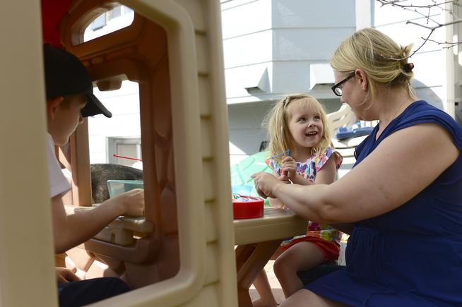 Emma Griffith, 3, smiles at her mother, Lauren while they play a game with her brother Luke 7, in the backyard while having a snack at their home on April